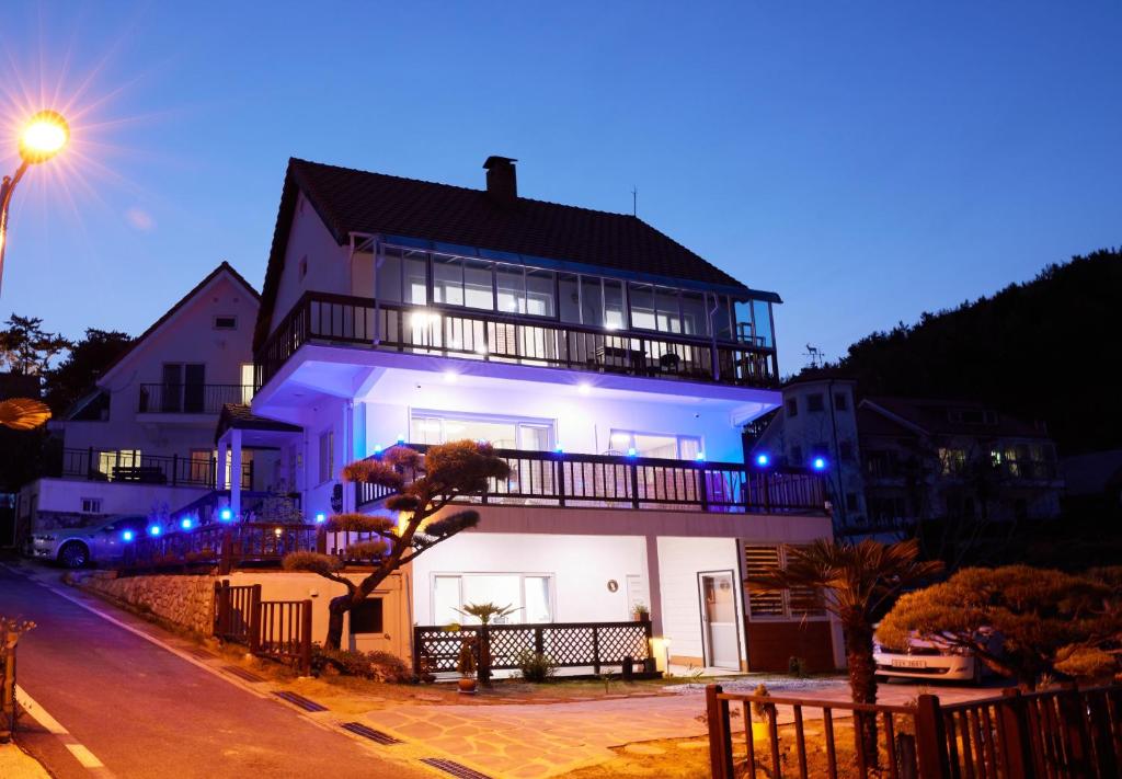 ein großes weißes Haus mit Balkon in der Nacht in der Unterkunft Herkules Namhae German Village in Namhae