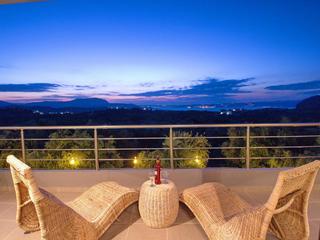 een balkon met rieten stoelen en een tafel met een fles bij Villa Kallisto Almyrida Crete in Plaka