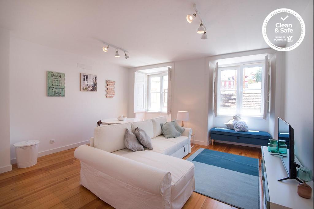 ein Wohnzimmer mit einem weißen Sofa und einem TV in der Unterkunft Alfama Premium by Homing in Lissabon