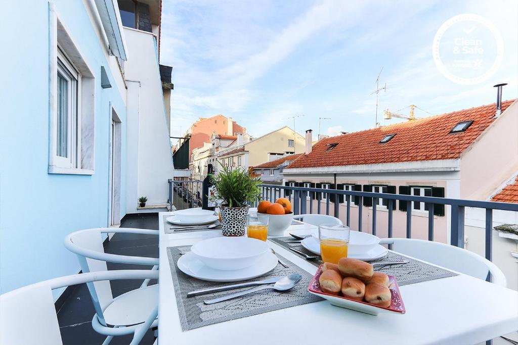 a white table with plates of food on a balcony at Estrela Terrace by Homing in Lisbon