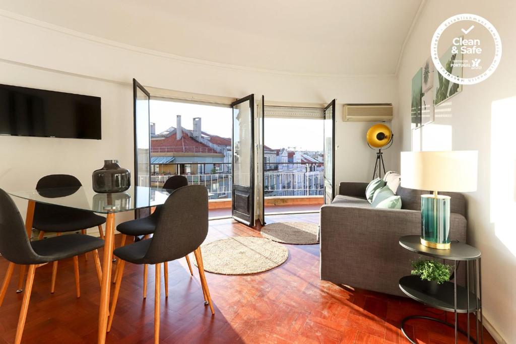 een woonkamer met een tafel en stoelen en een bank bij Marques Balcony by Homing in Lissabon