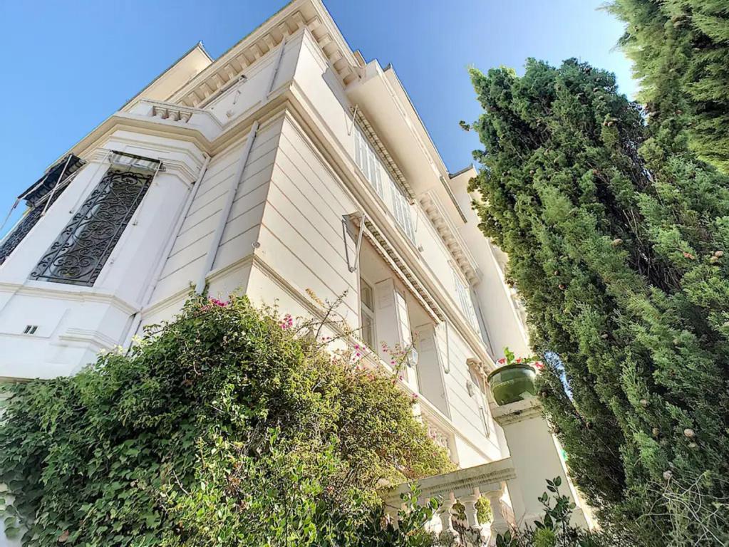 un grand bâtiment blanc avec une tour d'horloge dans l'établissement Charmant appartement dans villa avec parc, à Cannes