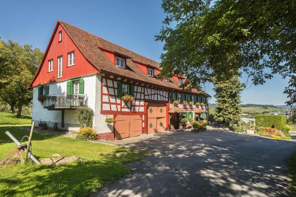 a large red and white house with a driveway at Ferienwohnung Risthof 1 in Owingen