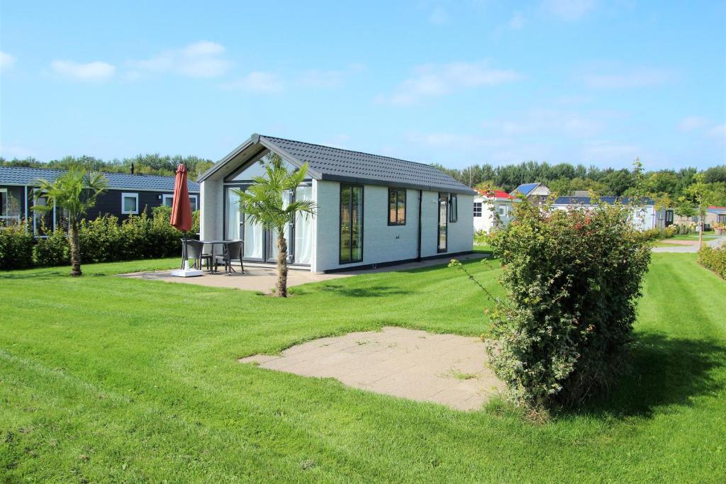 ein kleines Haus in einem Garten mit grünem Rasen in der Unterkunft Chalet Sky de luxe in Drijber