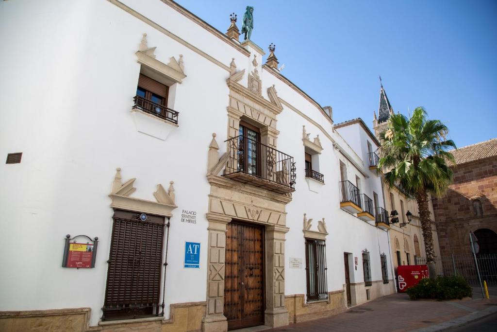 a white building with a wooden door on a street at Palacio Sirvente Mieres - PARKING GRATUITO in Andújar