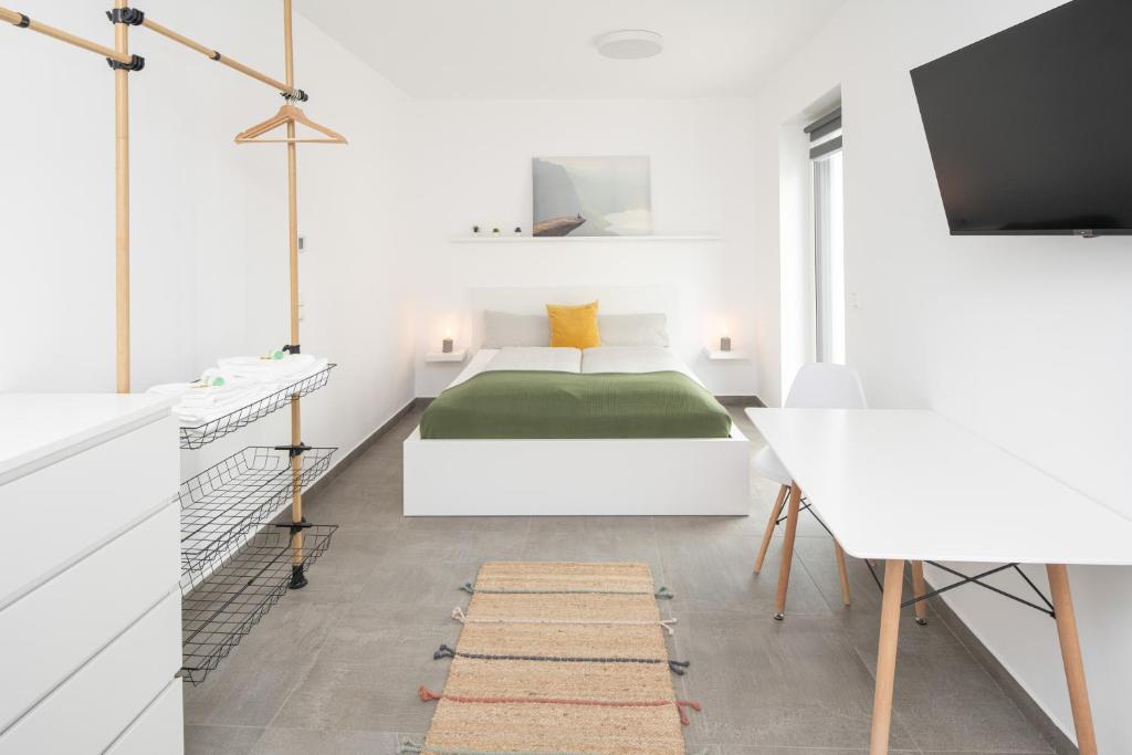 een witte slaapkamer met een bed en een bureau bij Nibelungen Apartments in Worms