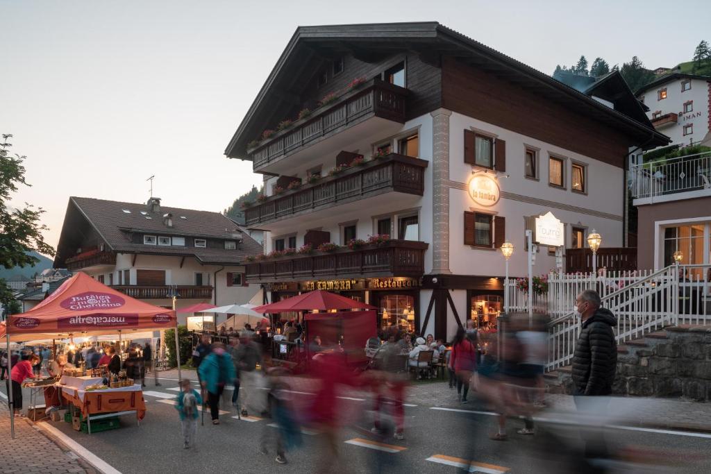 a group of people walking down a street in front of a building at La Tambra - Residence - Central with Restaurant in Santa Cristina Gherdëina