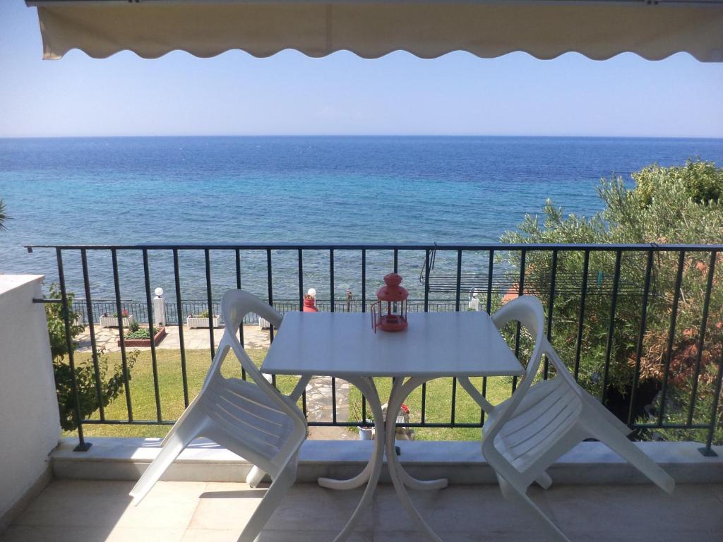 a table and two chairs on a balcony with the ocean at Alexiadis Apartments in Agia Paraskevi