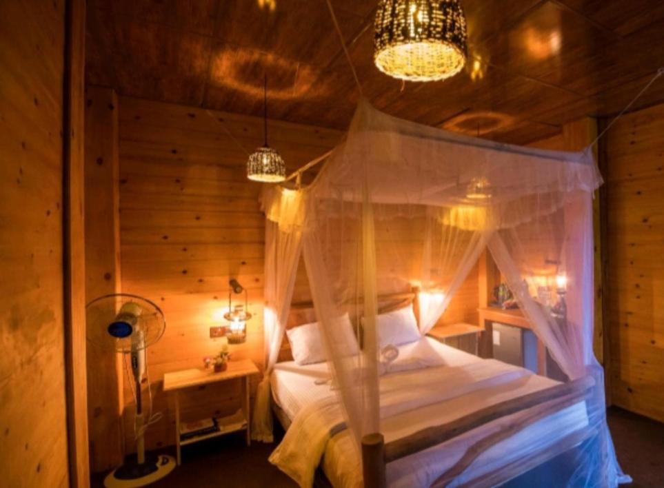 1 dormitorio con 1 cama con dosel en Ella Wood Cabin en Ella