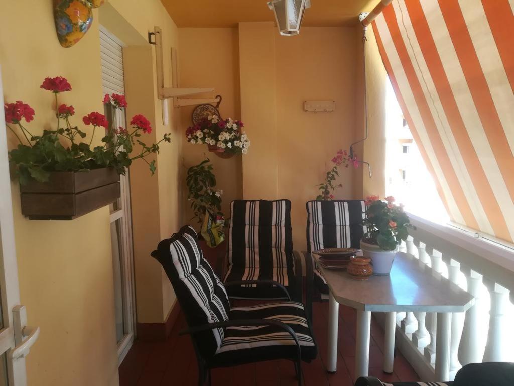 マラガにあるComo en casaの椅子2脚、テーブル、窓が備わる客室です。