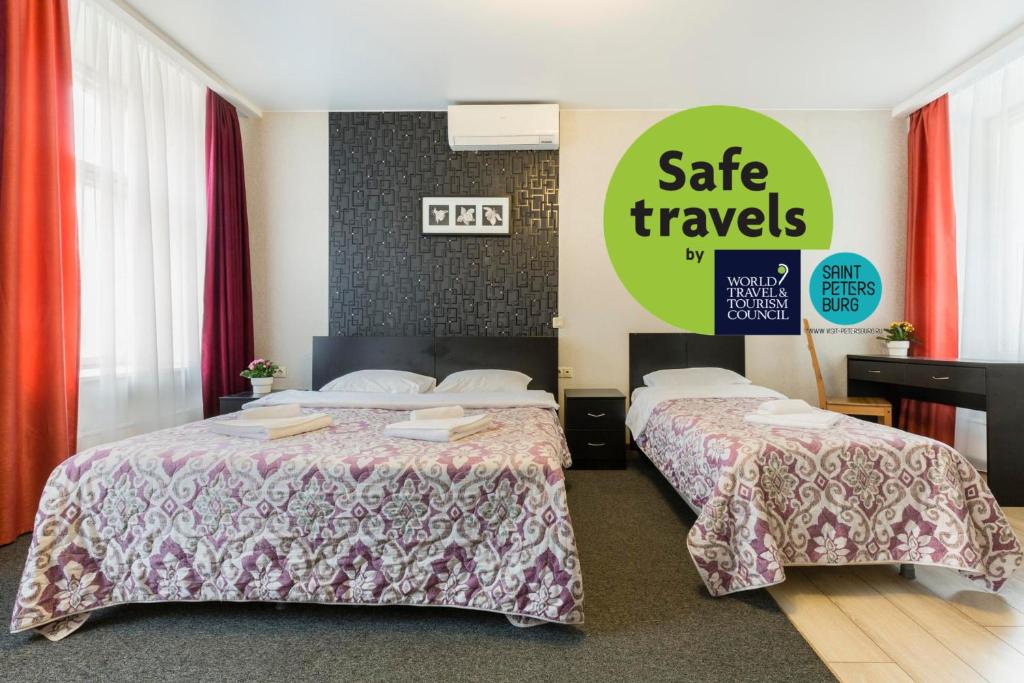 a hotel room with two beds and a sign that says safe travels at Amber Hotel in Saint Petersburg