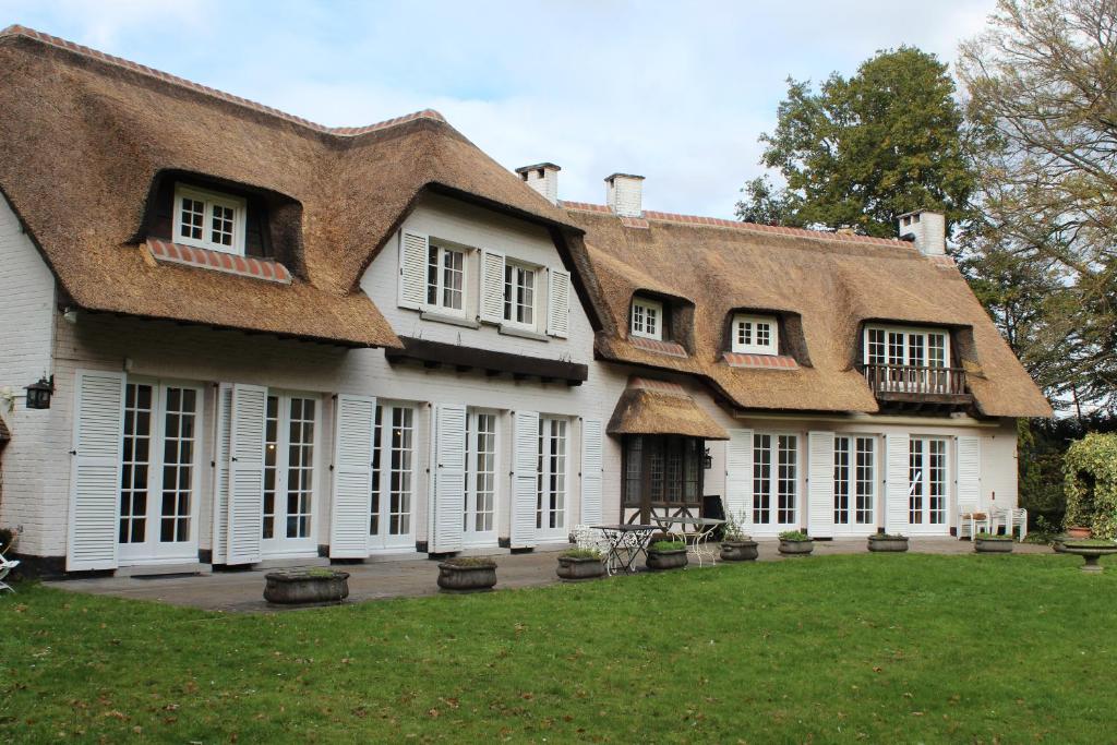 a large white house with a thatched roof at Villa Monceau Louvain la neuve in Louvain-la-Neuve