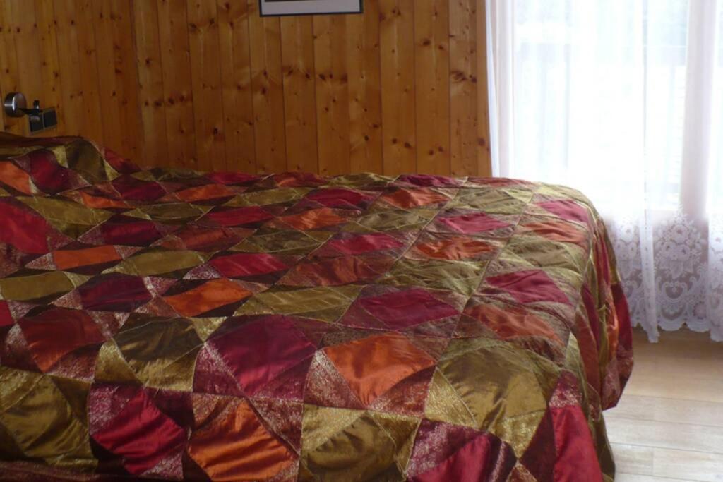 a bed with a colorful quilt in a bedroom at Le chalet de Julbert in Combloux