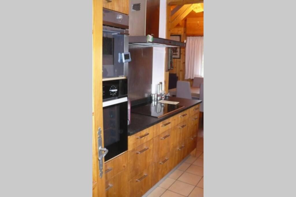 a kitchen with wooden cabinets and a stove top oven at Le chalet de Julbert in Combloux