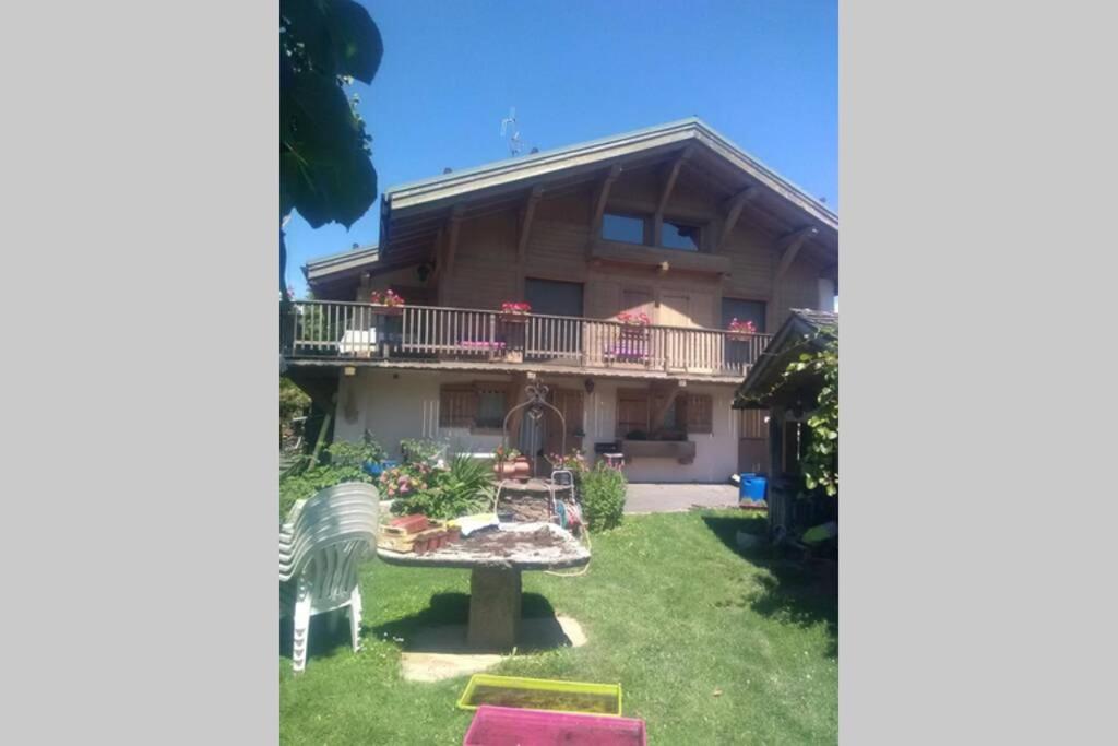 a house with a balcony and a yard at Le chalet de Julbert in Combloux