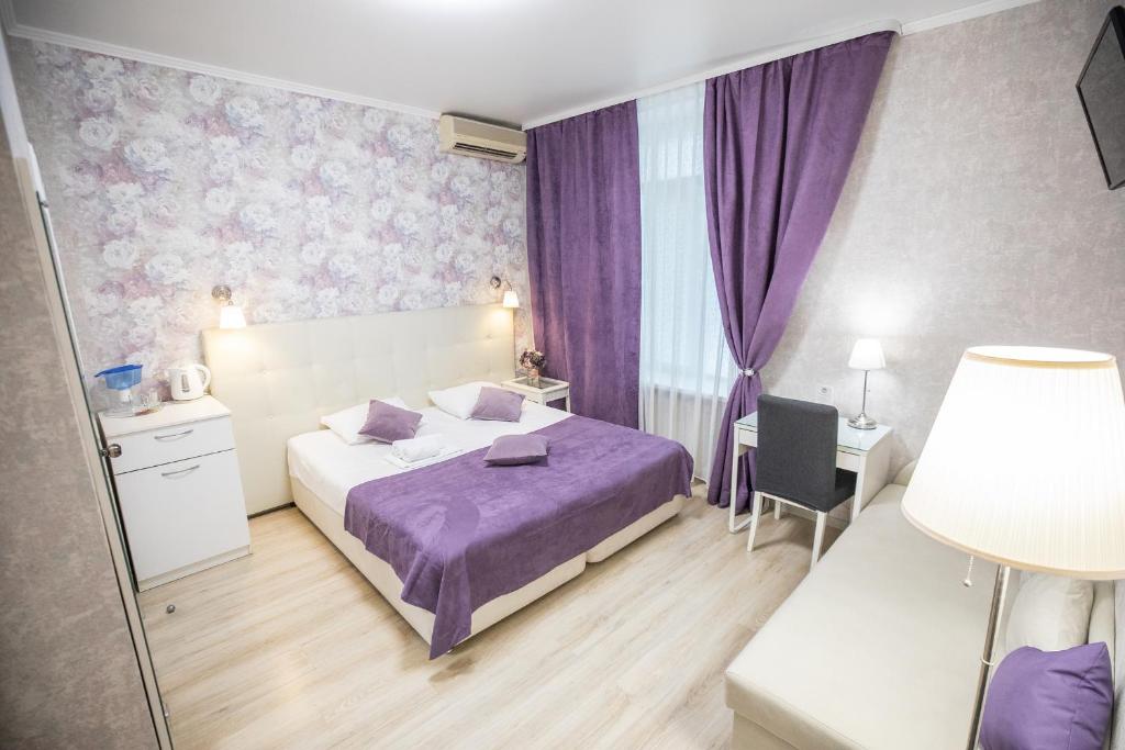 um quarto com uma cama roxa e cortinas roxas em Hotel A em Saratov