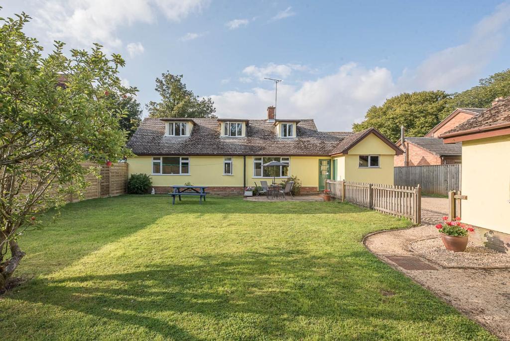 una casa amarilla con un patio con una valla en The Spinney Saxtead nr Framlingham Air Manage Suffolk, en Woodbridge