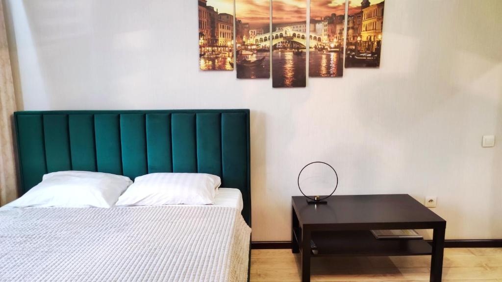 a bed with a green headboard next to a table at Apartment Lenina in Vladimir