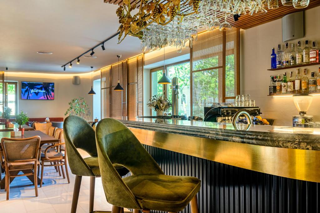 a bar with two green chairs and a counter at Villa Pinia Eco-hotel in Odesa
