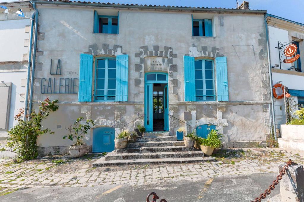 stary dom z niebieskimi okiennicami i schodami w obiekcie La Maison Galerie w mieście Mornac-sur-Seudre
