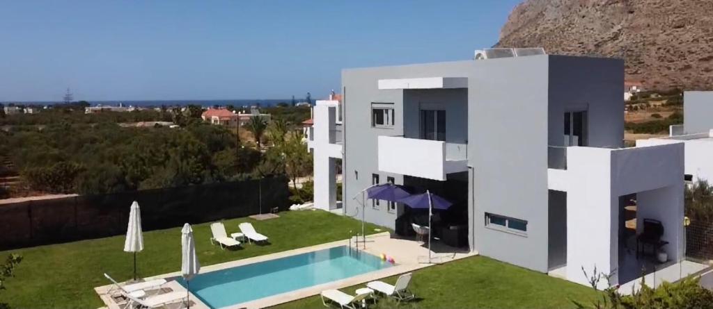 a white house with a swimming pool in front of it at Helios a modern large villa with private pool set in a quiet location in Stavros