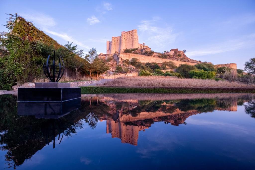 un castillo sentado en la cima de una colina junto a un lago en Alila Fort Bishangarh Jaipur - A Hyatt Brand, en Jaipur