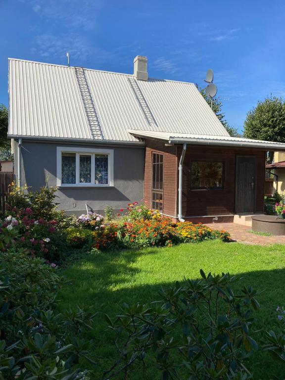 a house with a roof and a yard with flowers at Brīvdienu māja Saulīte in Ventspils