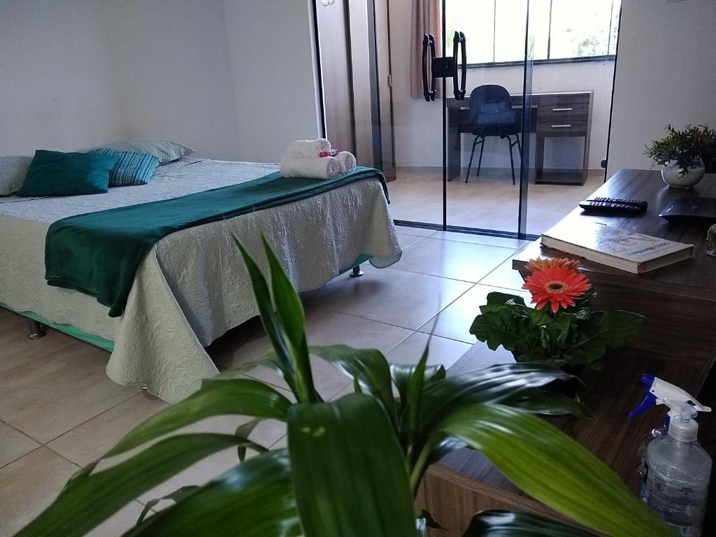 1 dormitorio con cama, mesa y planta en Aconchego da Floresta, en Angra dos Reis
