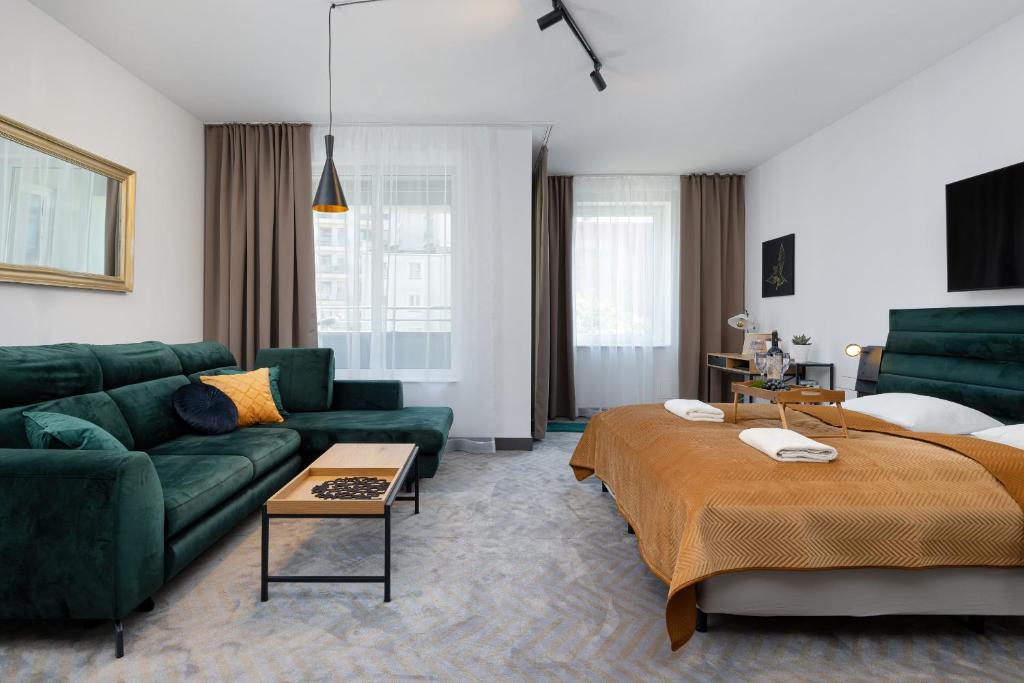 a living room with a green couch and a bed at Etna Apartments Kołobrzeg by Renters in Kołobrzeg
