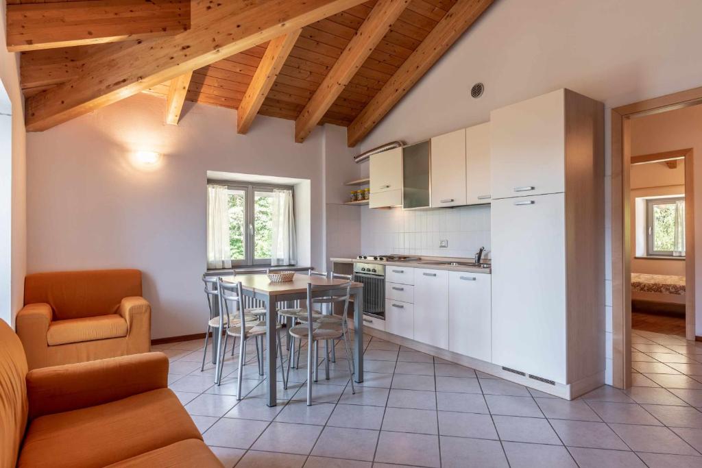 a kitchen with white cabinets and a table and chairs at Appartamento alla Preda Grauno Ospitar in Grauno