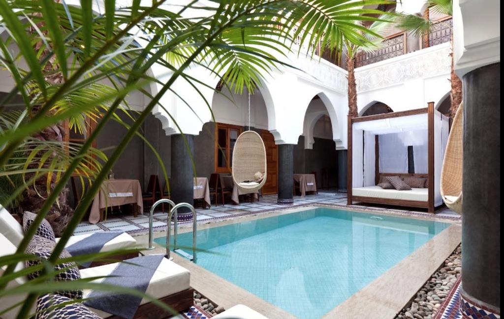 a pool in a hotel with a palm tree at Hotel & Spa Riad El Walaa in Marrakech