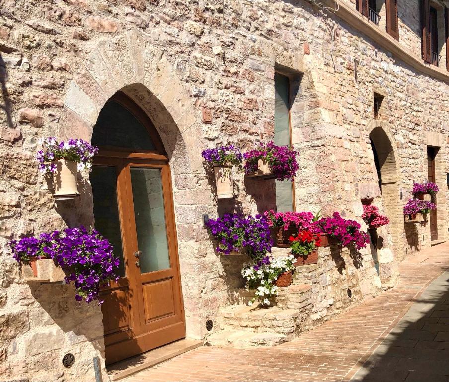un bâtiment en pierre avec des boîtes de fleurs et une porte dans l'établissement Camere Capobove Assisi, à Assise