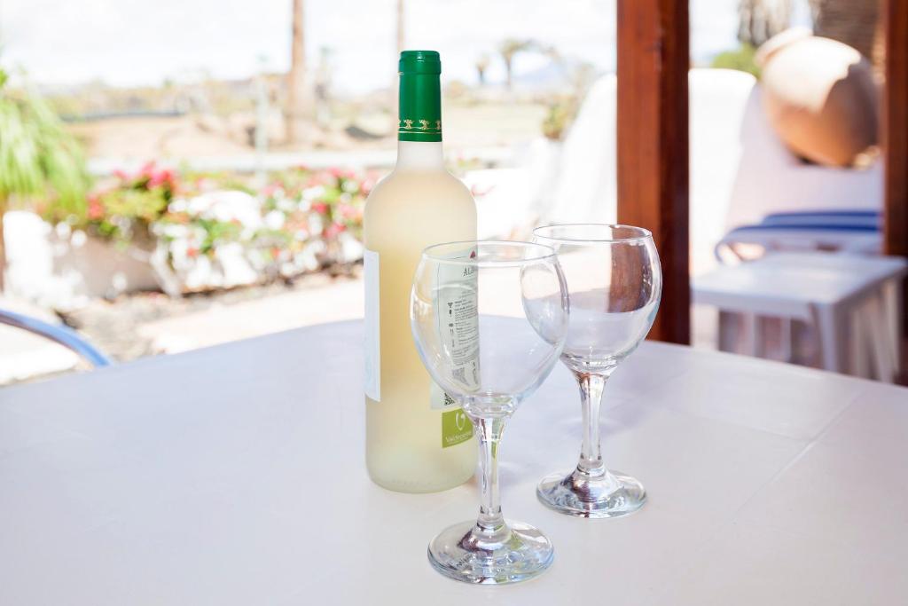 a bottle of wine and two wine glasses on a table at Casa Bonita, Golf del Sur in San Miguel de Abona