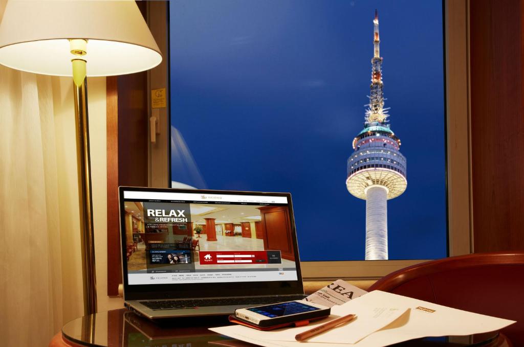 a laptop computer sitting on a desk with a view of the tv tower at Sejong Hotel Seoul Myeongdong in Seoul