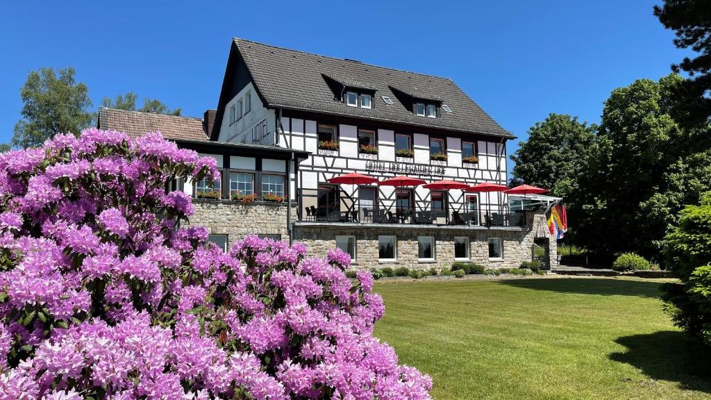 ein Haus mit rosa Blumen davor in der Unterkunft Boutique Hotel Restaurant Hollerather Hof in Hellenthal