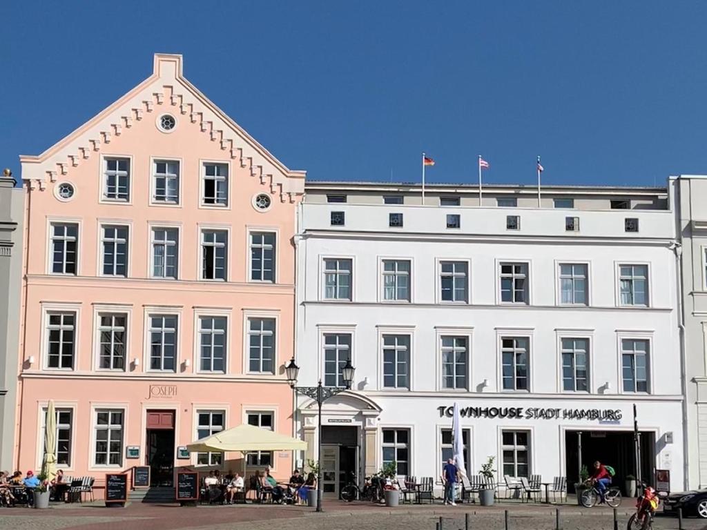 維斯馬的住宿－Townhouse Stadt Hamburg Wismar，一座白色的大建筑,外面的人坐在