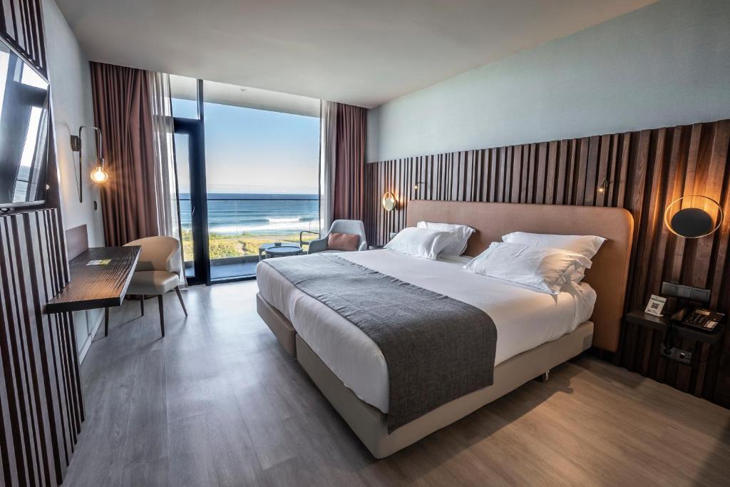 a bedroom with a bed and a view of the ocean at Hotel Verde Mar & SPA in Ribeira Grande