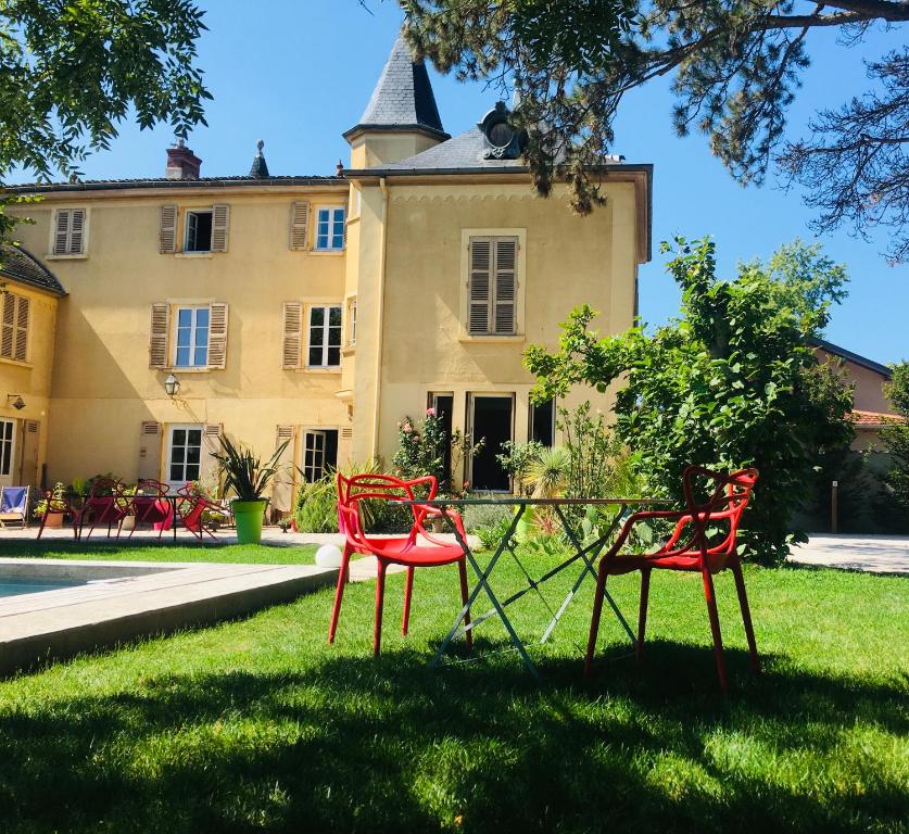two red chairs sitting in the grass in front of a building at Aux Tourelles 1888 - Tres Proche Lyon #Clim #Piscine #Netflix #Parking Payant Securise in Tassin-la-Demi-Lune