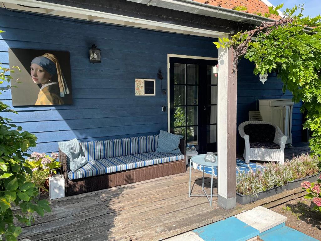 une maison bleue avec un canapé sur une terrasse en bois dans l'établissement Bed en breakfast Onder aan de dijk, à Warder