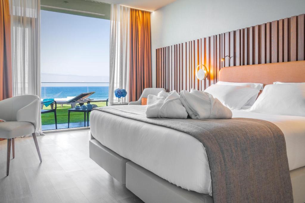 a bedroom with a large bed with a view of the ocean at Hotel Verde Mar & SPA in Ribeira Grande