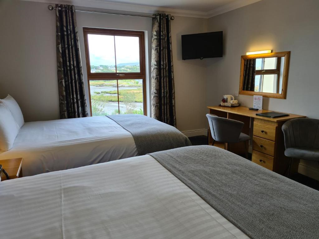 a hotel room with two beds and a desk and a window at Caisleain Oir Hotel in Annagry