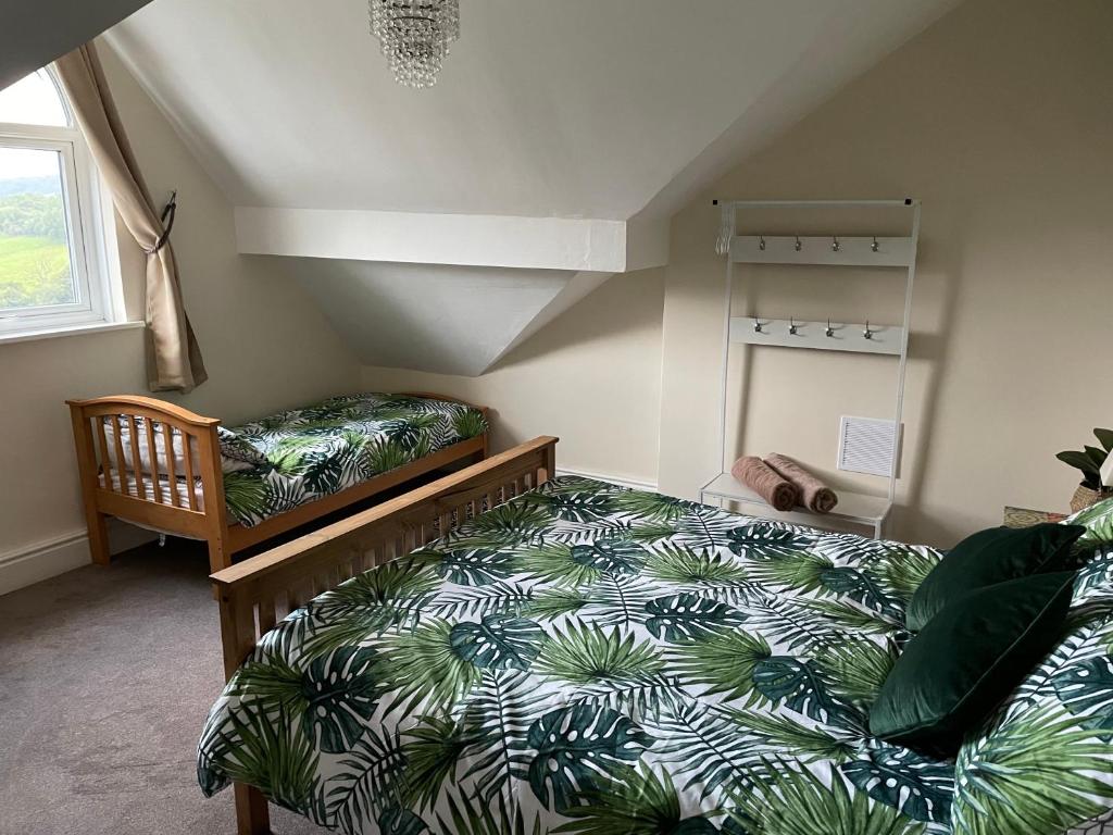 a bedroom with a bed with a green and white comforter at Danbury Lodge Penthouse in Matlock