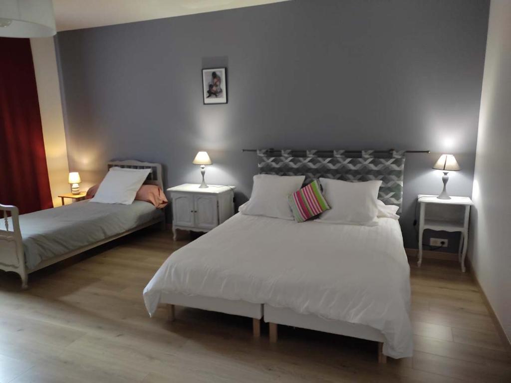 1 dormitorio con 2 camas, 2 mesas y 2 lámparas en Maison Gîte Nanie en Arbois