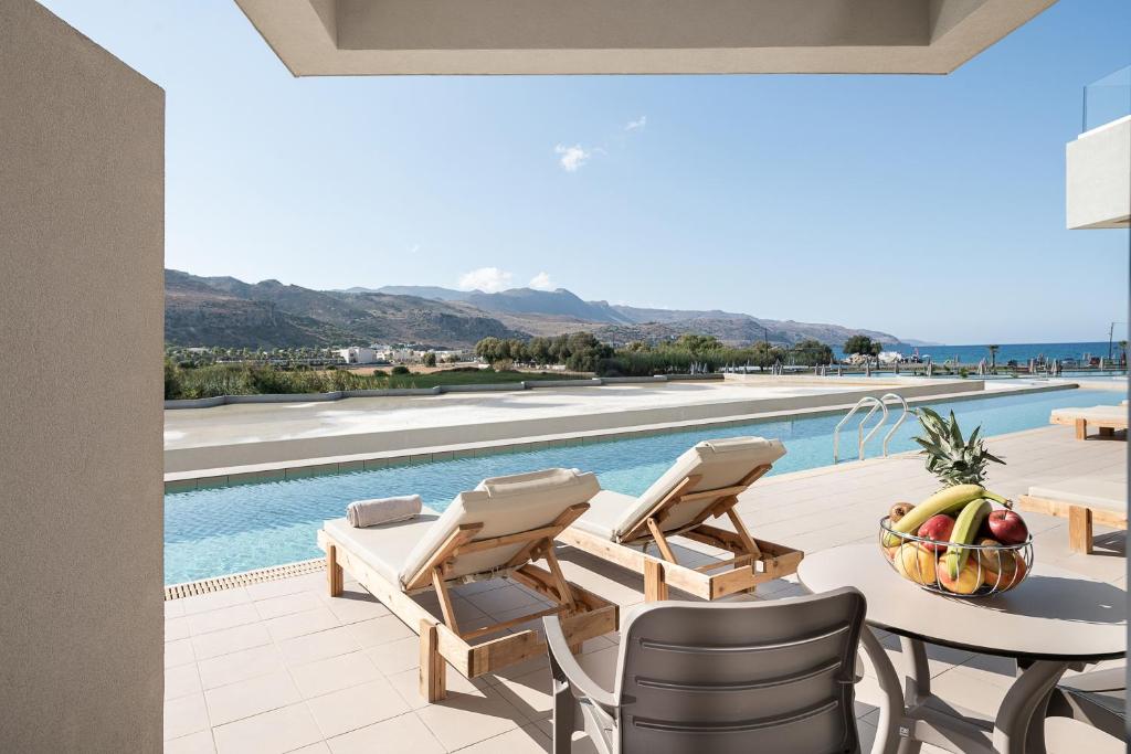 een patio met een tafel en stoelen en een zwembad bij Galini Palace in Kolymvari