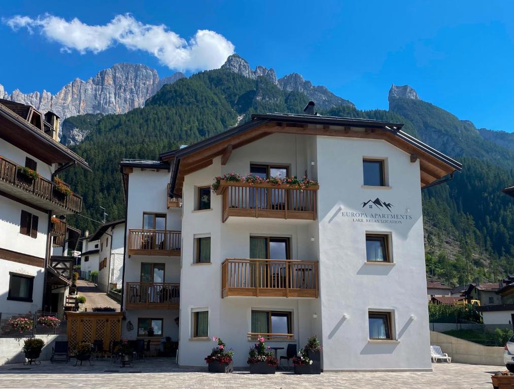 un edificio con balcone e montagne sullo sfondo di Europa Mountain Apartments ad Alleghe