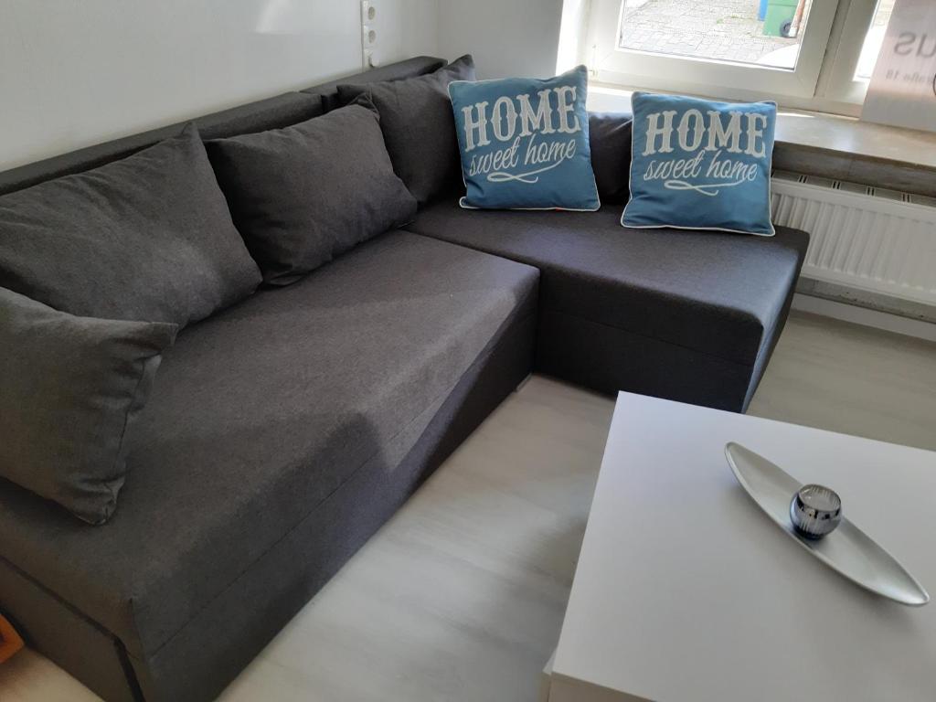 um sofá cinzento com duas almofadas e uma mesa em Ferienhaus Heide Zentrum em Heide