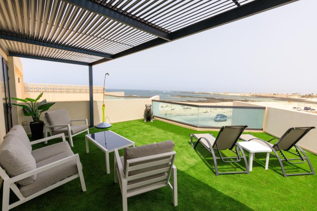 a patio with chairs and tables and a view of the ocean at BRUNO'S HOME in El Cotillo