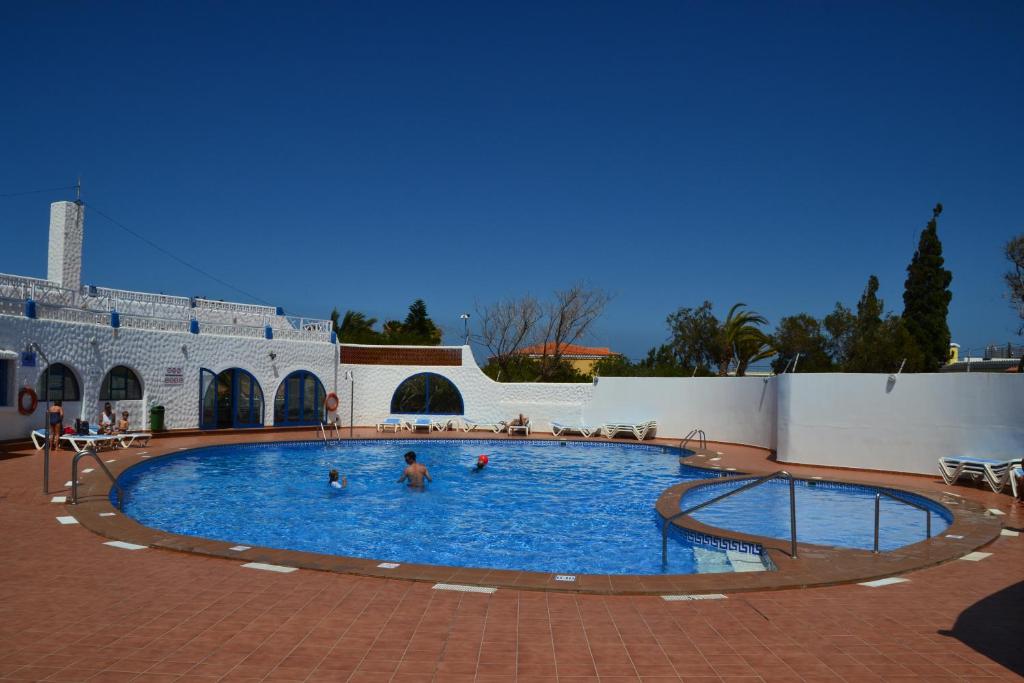 a large swimming pool with people in the water at Chalet Canarias in Telde