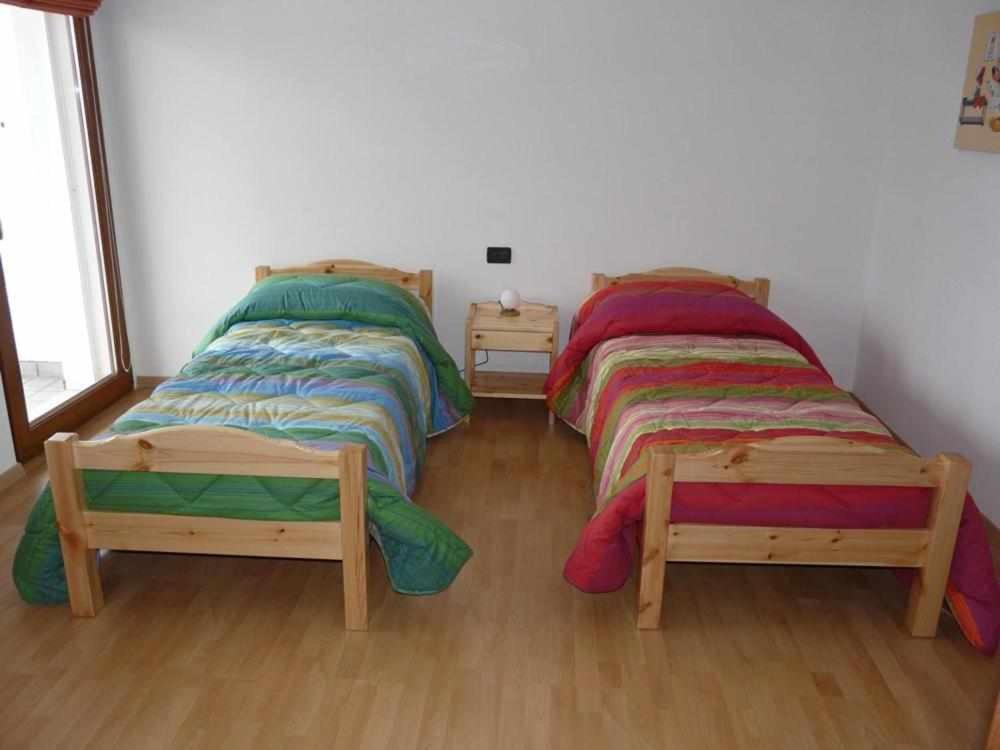 2 Einzelbetten in einem Zimmer mit Holzböden in der Unterkunft Casa Vacanze IL BEARČ in Feltrone