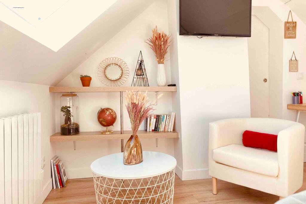 - un salon avec une chaise blanche et une table dans l'établissement Sous Les Nuages, à Rouen